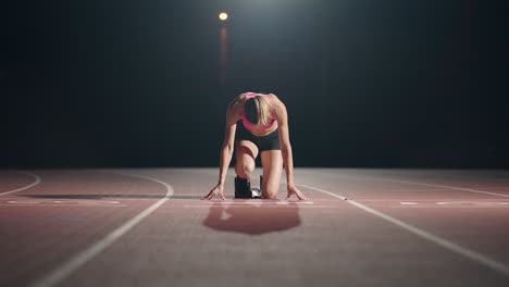 Vista-Frontal-De-Una-Atleta-Femenina-Comenzando-Su-Sprint-En-Una-Pista-De-Atletismo.-Corredor-Despegando-Desde-La-Parrilla-De-Salida-En-La-Pista-De-Atletismo.-Cámara-Con-Zoom.-Camara-Lenta